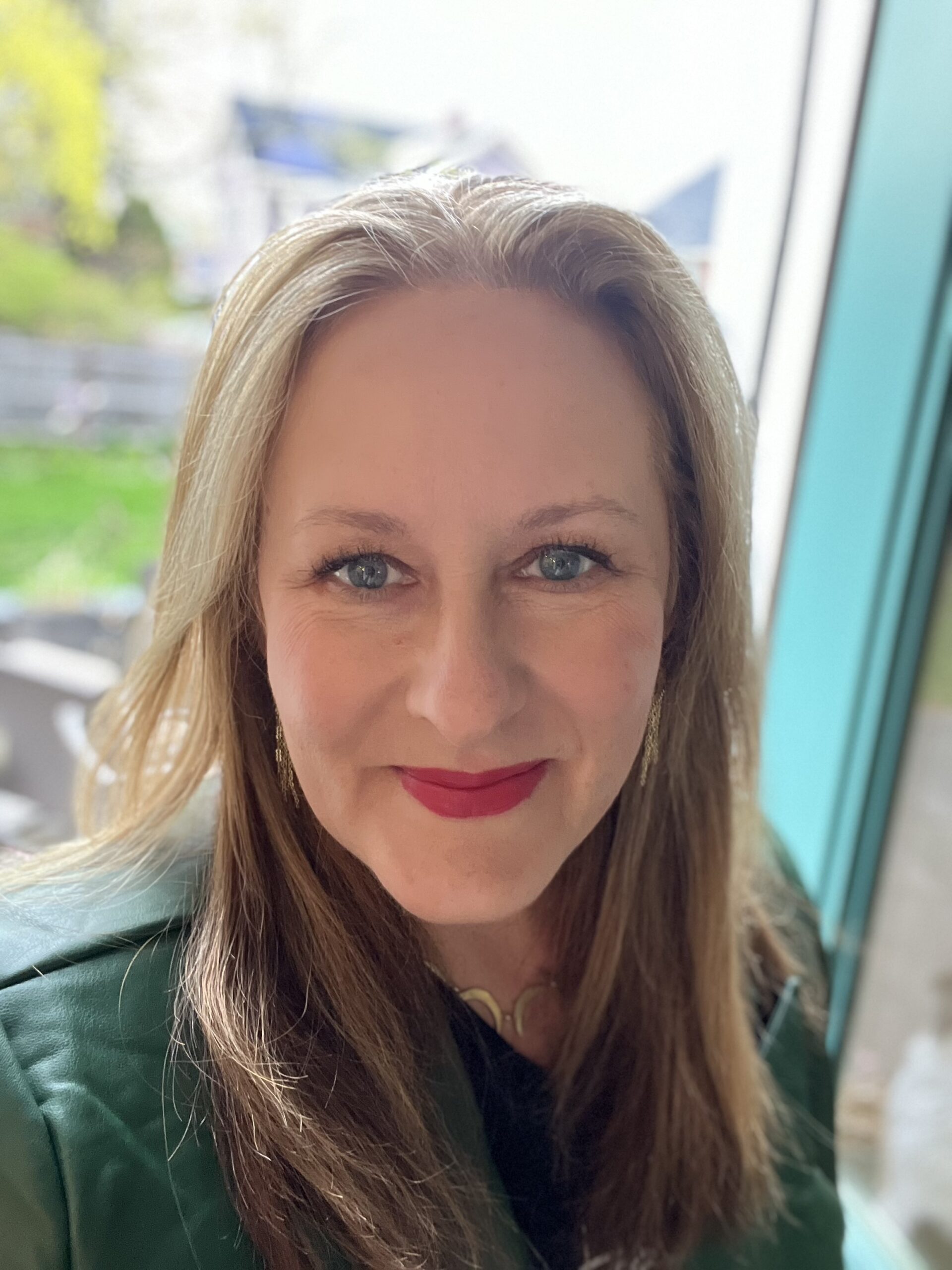 Headshot of Jen Cook Johnson sitting in front of a blue window